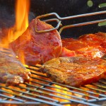 Fleisch auf dem Grill wird mit einer Grillzange gewendet